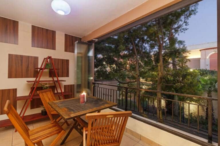 Balcony dining area with wooden furniture overlooking a treetop view at dusk