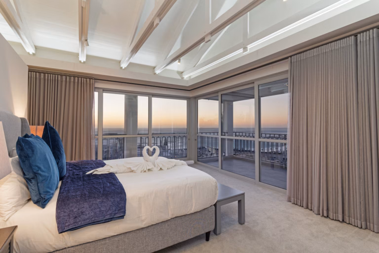 Luxury bedroom with panoramic ocean views and swan towel art on the bed